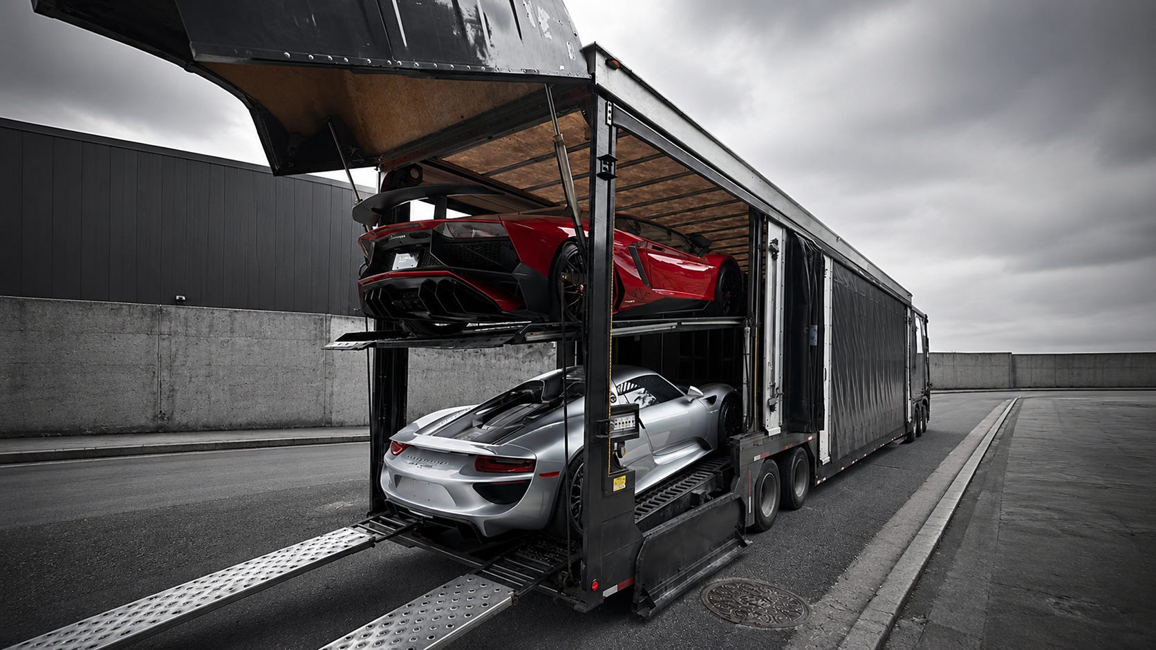 Enclosed transporter loading a Lamborghini and a Porsche for delivery