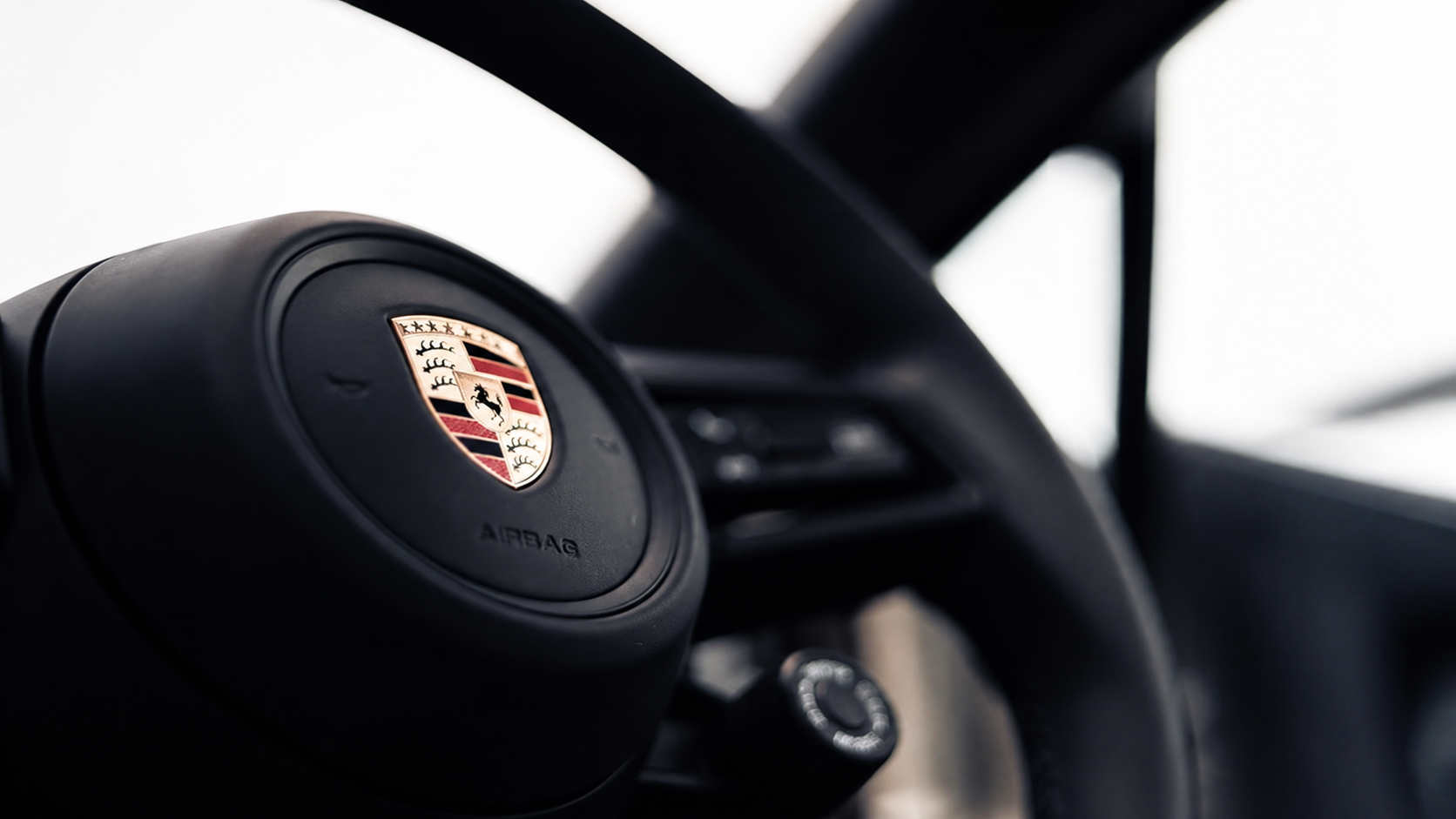 Portfolio strategy — detail of the Porsche crest on a steering wheel